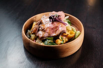 Salad with beef, fried potatoes and pickled cucumber